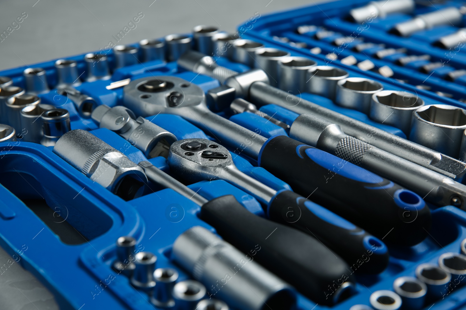 Photo of Different auto mechanic's tools in plastic box on grey table, closeup