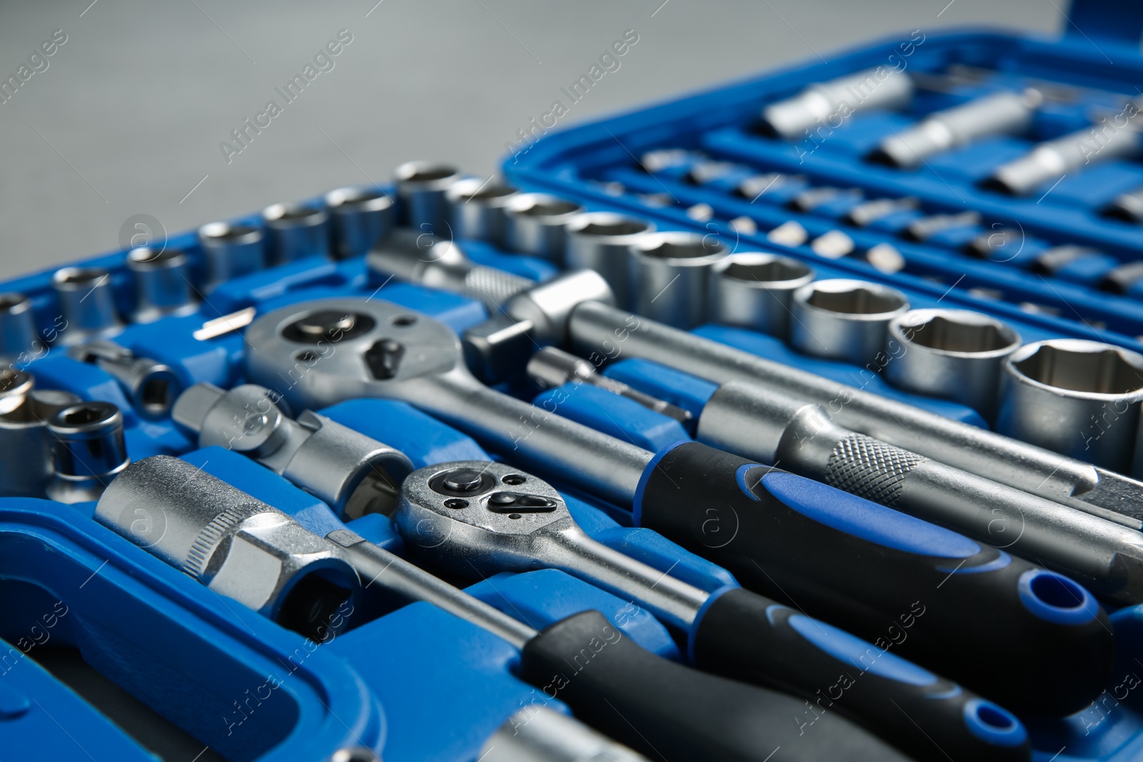 Photo of Different auto mechanic's tools in plastic box on grey table, closeup