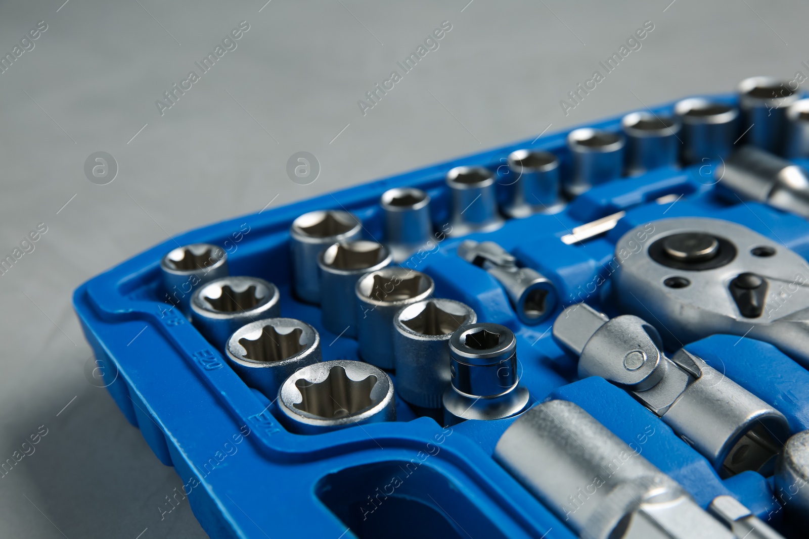 Photo of Different auto mechanic's tools in plastic box on grey table, closeup