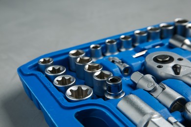 Photo of Different auto mechanic's tools in plastic box on grey table, closeup