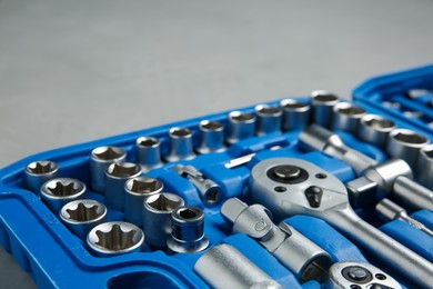 Photo of Different auto mechanic's tools in plastic box on grey table, closeup