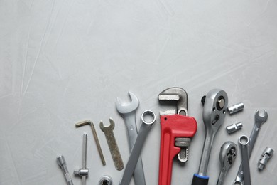 Different auto mechanic's tools on grey table, flat lay. Space for text