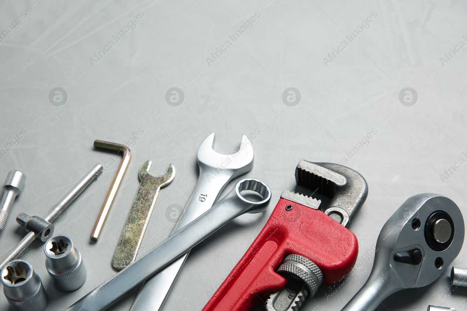 Photo of Different auto mechanic's tools on grey table, space for text