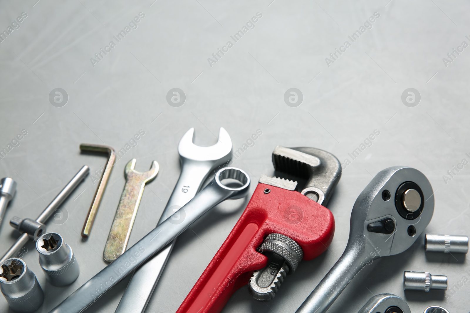 Photo of Different auto mechanic's tools on grey table, space for text