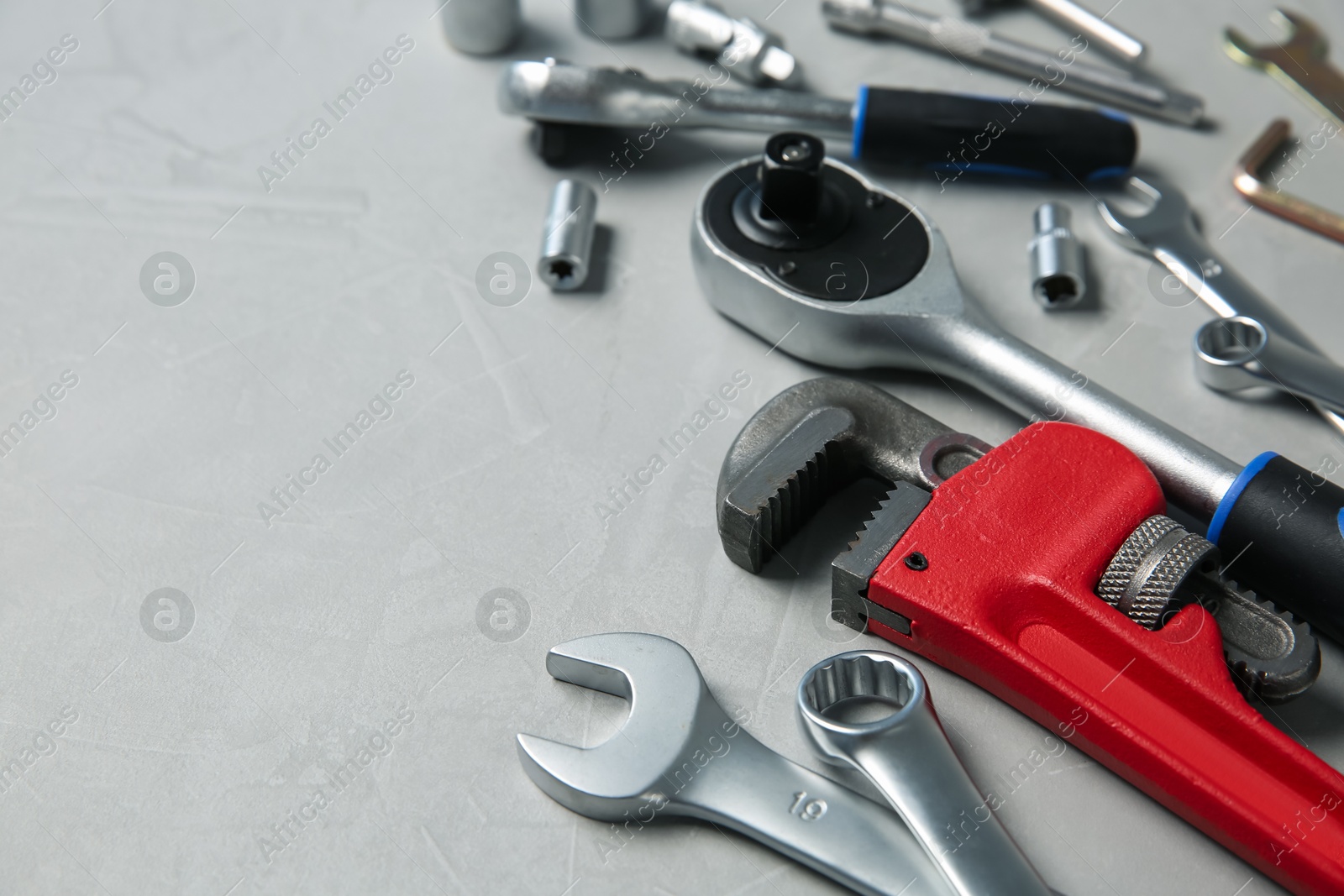 Photo of Different auto mechanic's tools on grey table, space for text