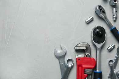 Different auto mechanic's tools on grey table, flat lay. Space for text