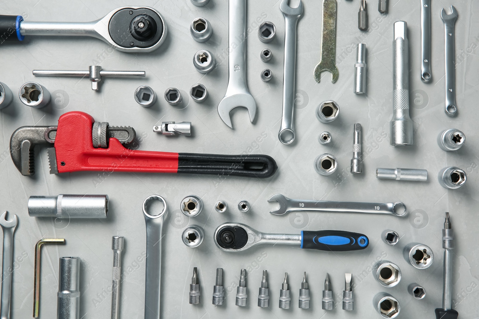 Photo of Different auto mechanic's tools on grey table, flat lay