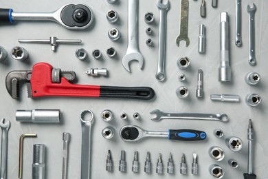 Different auto mechanic's tools on grey table, flat lay