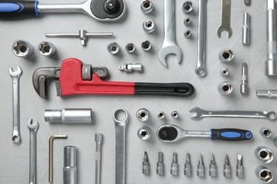 Different auto mechanic's tools on grey table, flat lay