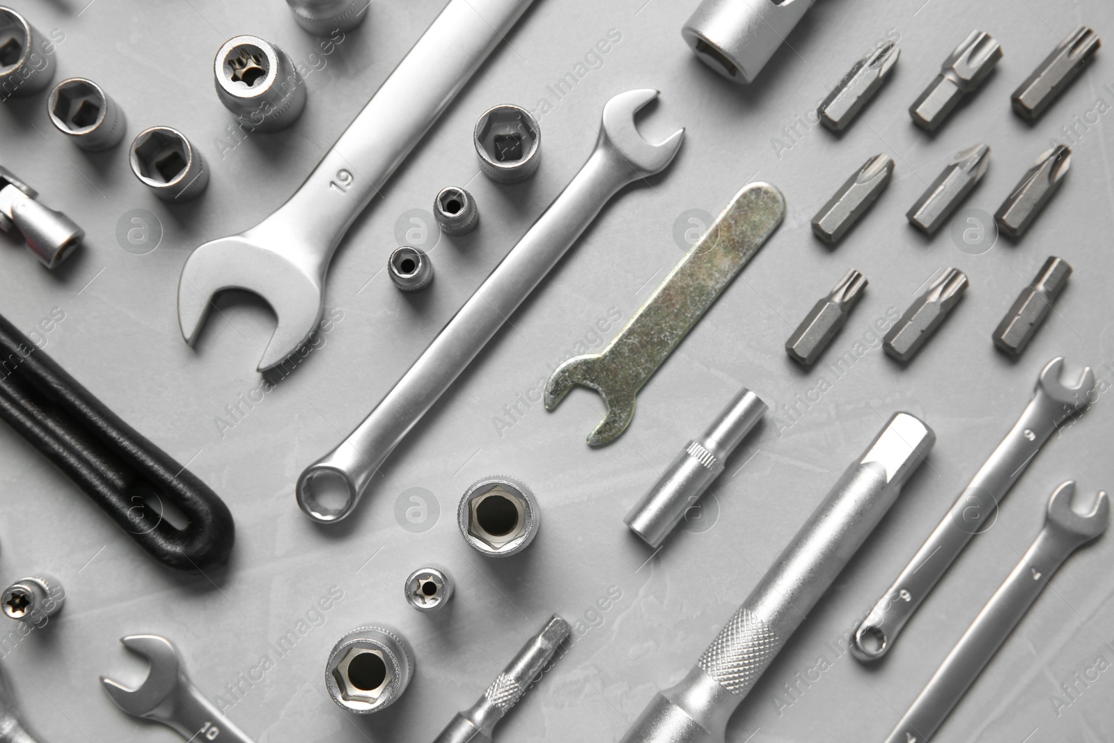 Photo of Different auto mechanic's tools on grey table, flat lay