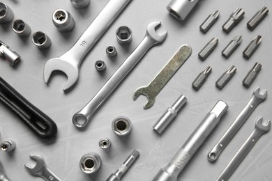 Different auto mechanic's tools on grey table, flat lay