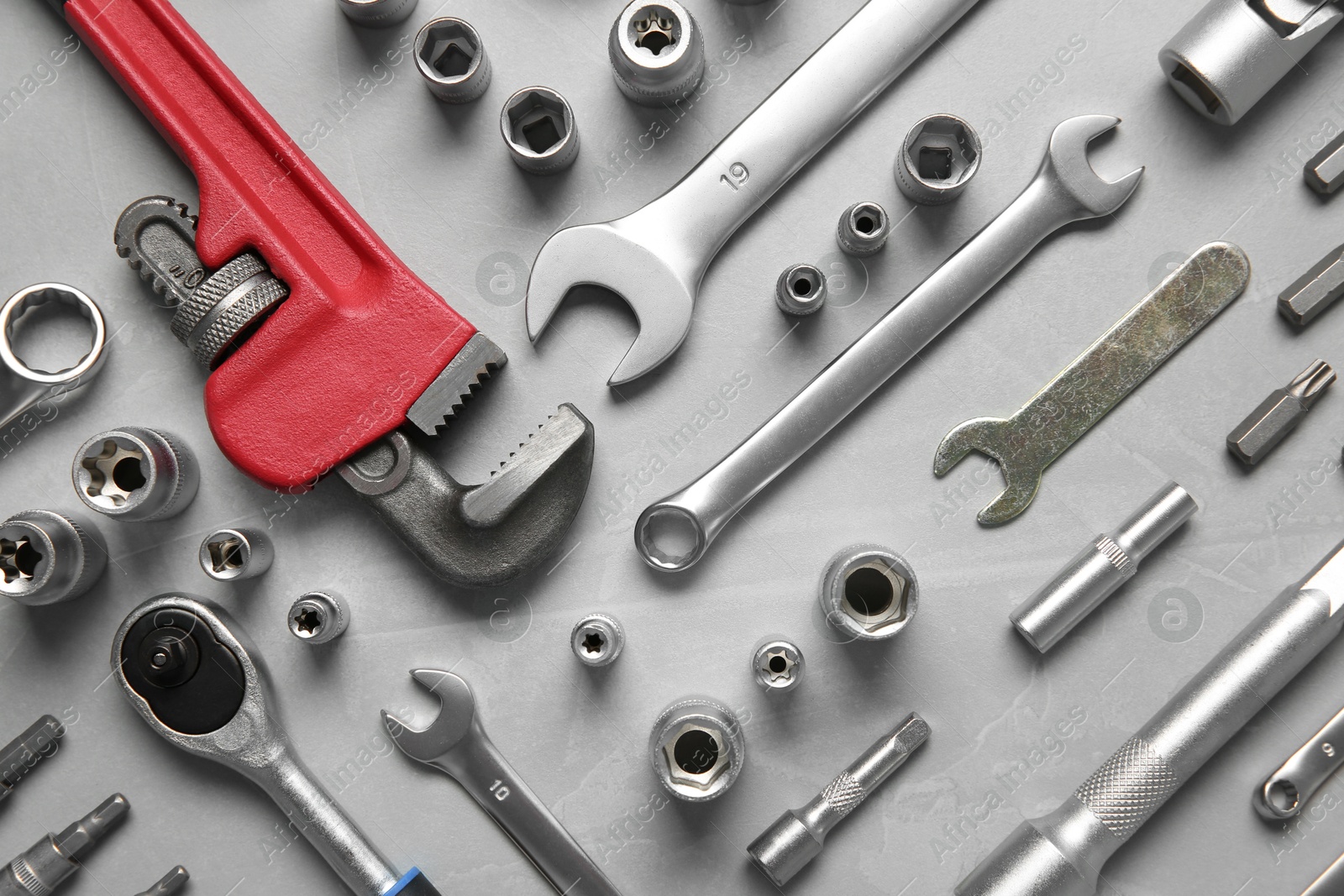 Photo of Different auto mechanic's tools on grey table, flat lay