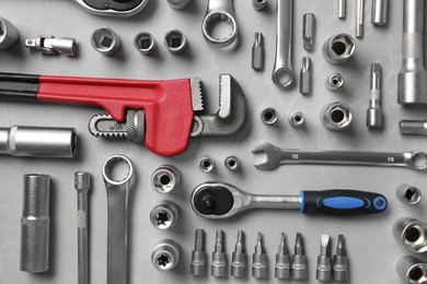 Different auto mechanic's tools on grey table, flat lay