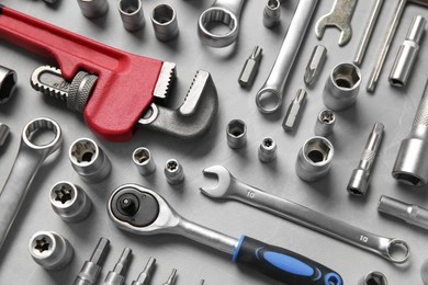 Different auto mechanic's tools on grey table, flat lay