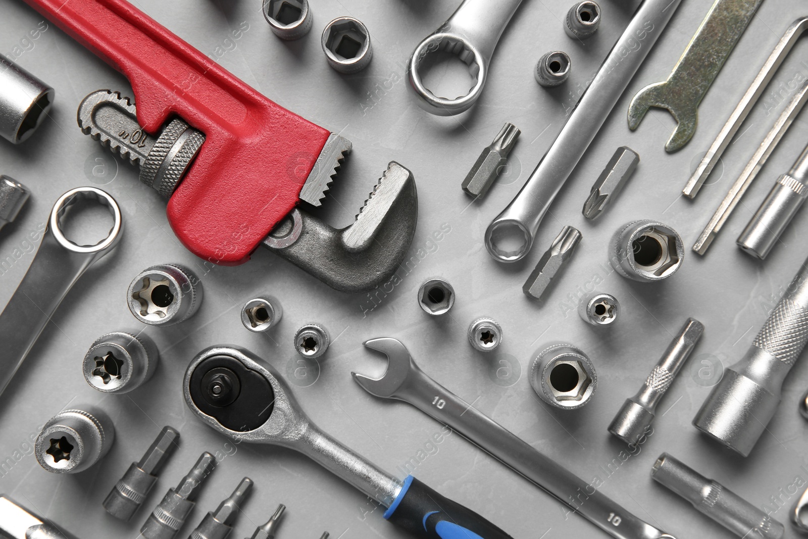 Photo of Different auto mechanic's tools on grey table, flat lay