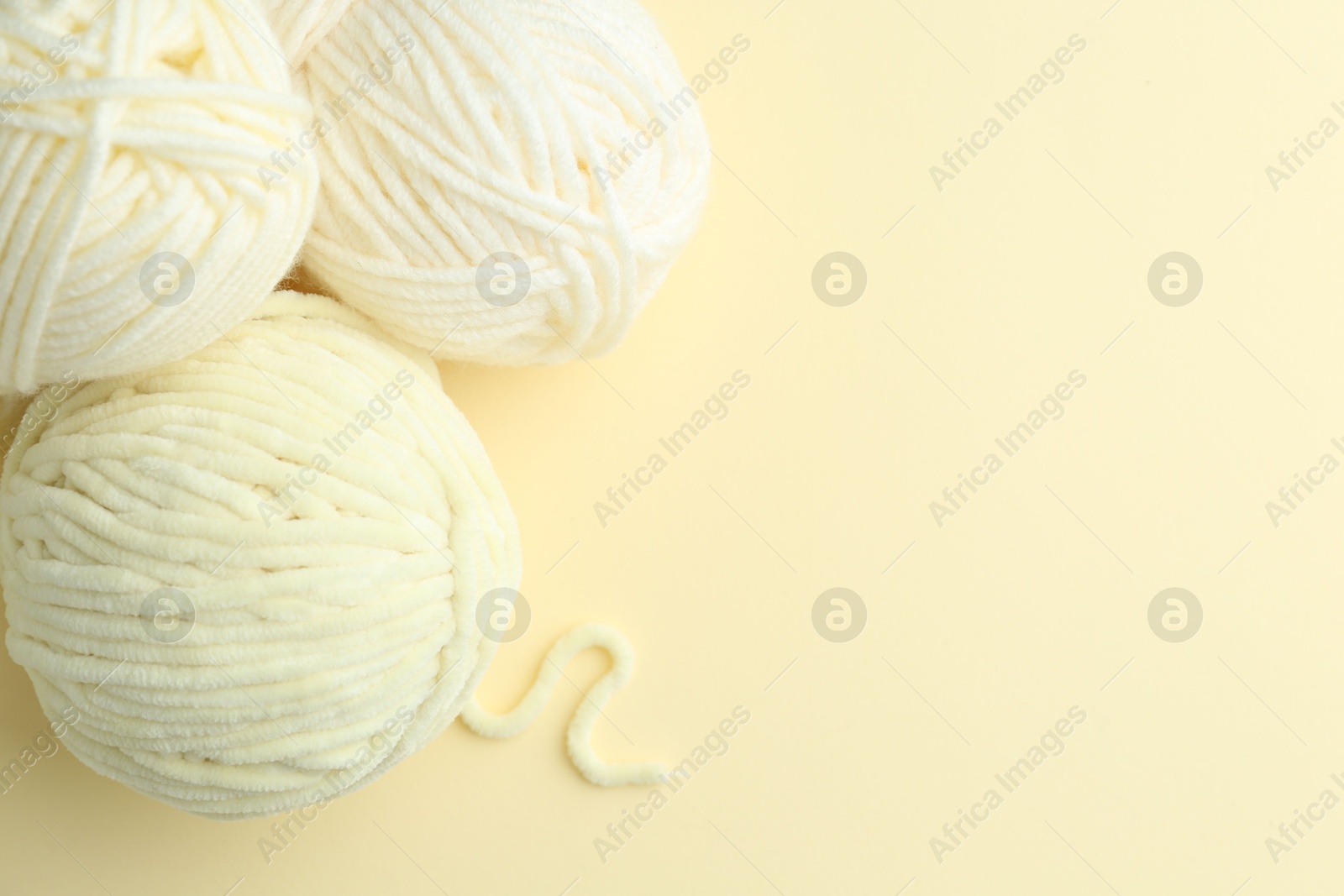 Photo of Skeins of plush yarn on beige background, flat lay with space for text. Knitting material