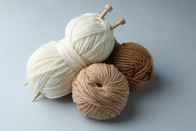 Skeins of yarn and knitting needles on light grey background