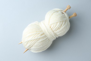 White yarn with knitting needles on light grey background, top view