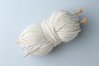 Photo of White yarn with knitting needles on light grey background, top view