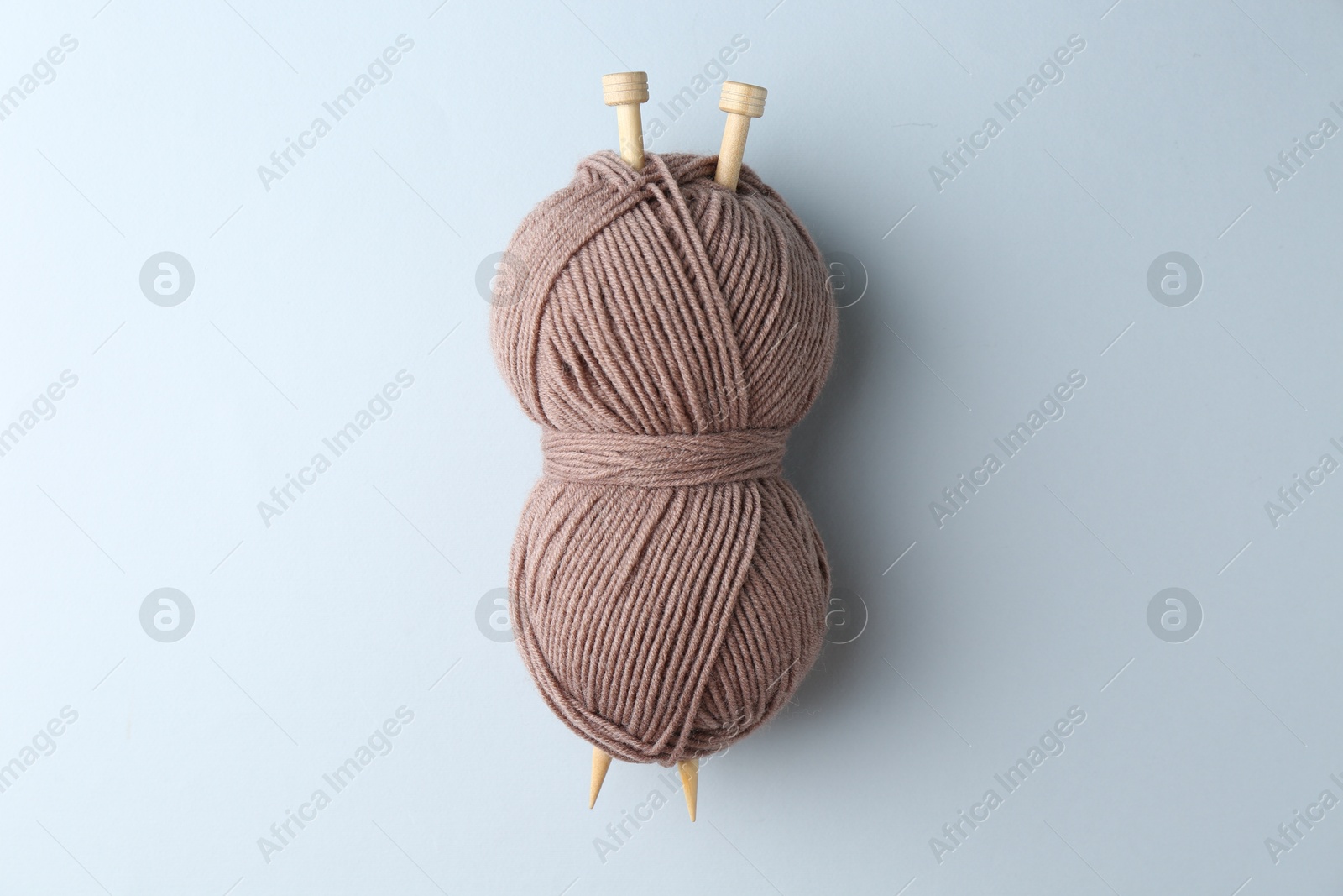 Photo of Brown yarn with knitting needles on light grey background, top view