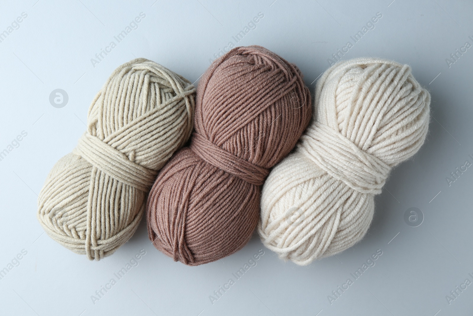 Photo of Different skeins of yarn on light grey background, flat lay. Knitting material