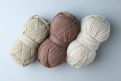 Photo of Different skeins of yarn on light grey background, flat lay. Knitting material