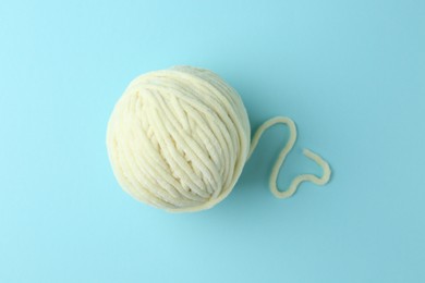 Ball of plush yarn on light blue background, top view. Knitting material