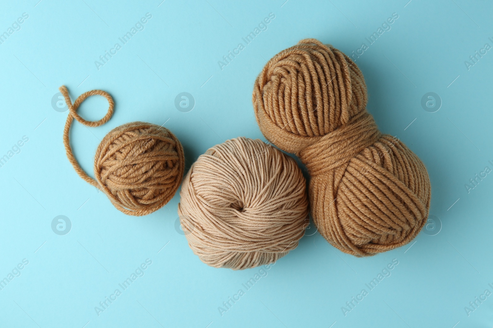 Photo of Skeins of yarn on light blue background, flat lay. Knitting material