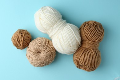 Photo of Skeins of yarn on light blue background, flat lay. Knitting material