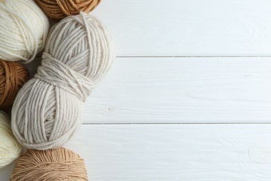 Photo of Skeins of different yarn on white wooden table, flat lay with space for text. Knitting material