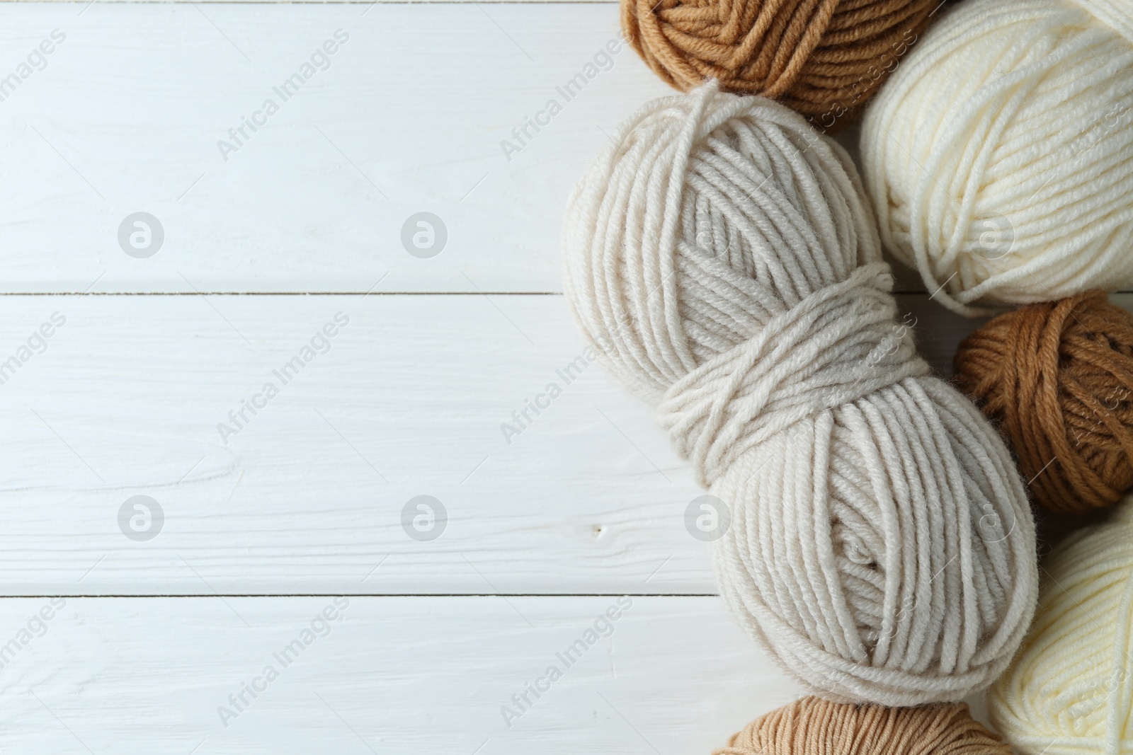 Photo of Skeins of different yarn on white wooden table, flat lay with space for text. Knitting material