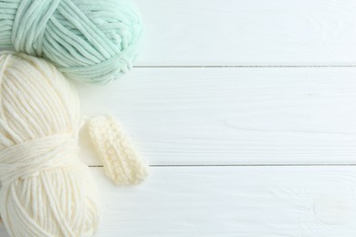 Photo of Skeins of yarn and pattern sample on white wooden table, flat lay. Space for text