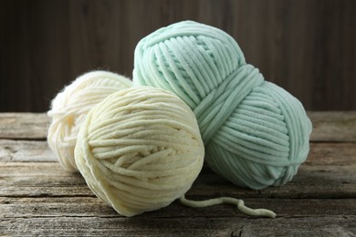 Three skeins of yarn on wooden table, closeup. Knitting material