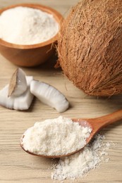 Photo of Fresh coconut flour in spoon, bowl and nuts on wooden table