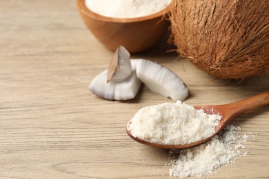 Photo of Fresh coconut flour in spoon, bowl and nuts on wooden table, space for text