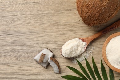 Photo of Fresh coconut flour in spoon, nuts and palm leaf on wooden table, flat lay. Space for text