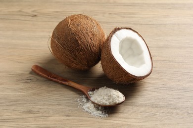 Photo of Fresh coconut flour in spoon and nuts on wooden table