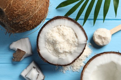 Photo of Fresh coconut flour, nuts, spoon and palm leaf on light blue wooden table, flat lay