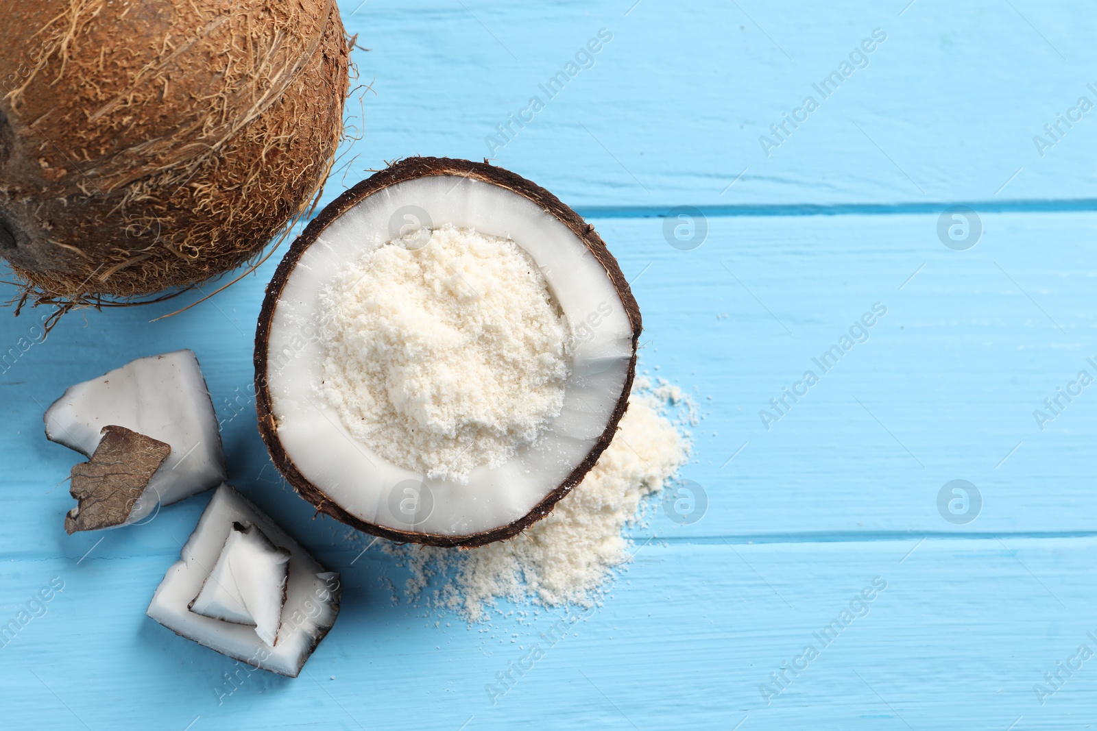 Photo of Fresh coconut flour and nuts on light blue wooden table, flat lay. Space for text