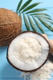 Photo of Fresh coconut flour, nuts and palm leaf on light blue wooden table