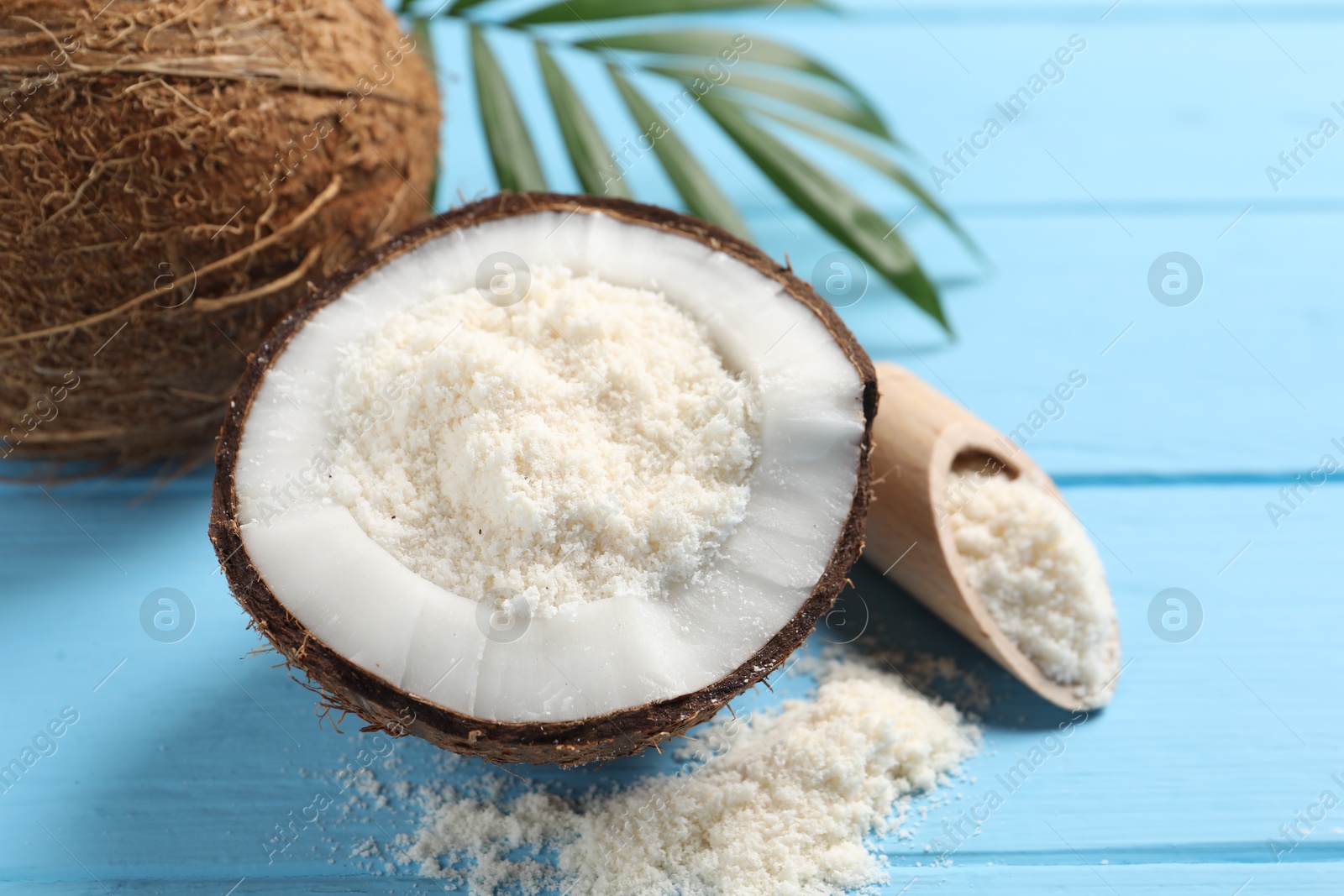 Photo of Fresh coconut flour, nuts and palm leaf on light blue wooden table