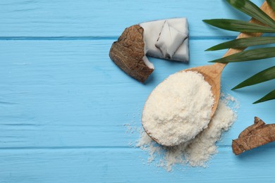 Photo of Fresh coconut flour in spoon, nut and palm leaf on light blue wooden table, flat lay. Space for text