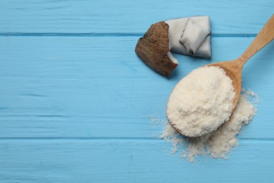 Photo of Fresh coconut flour in spoon and nut on light blue wooden table, top view. Space for text