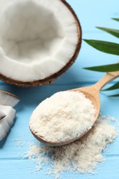 Photo of Fresh coconut flour in spoon, nut and palm leaf on light blue wooden table