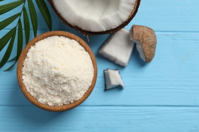 Photo of Fresh coconut flour in bowl, nut and palm leaf on light blue wooden table, flat lay