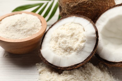 Photo of Fresh coconut flour, nuts, bowl and palm leaf on wooden table