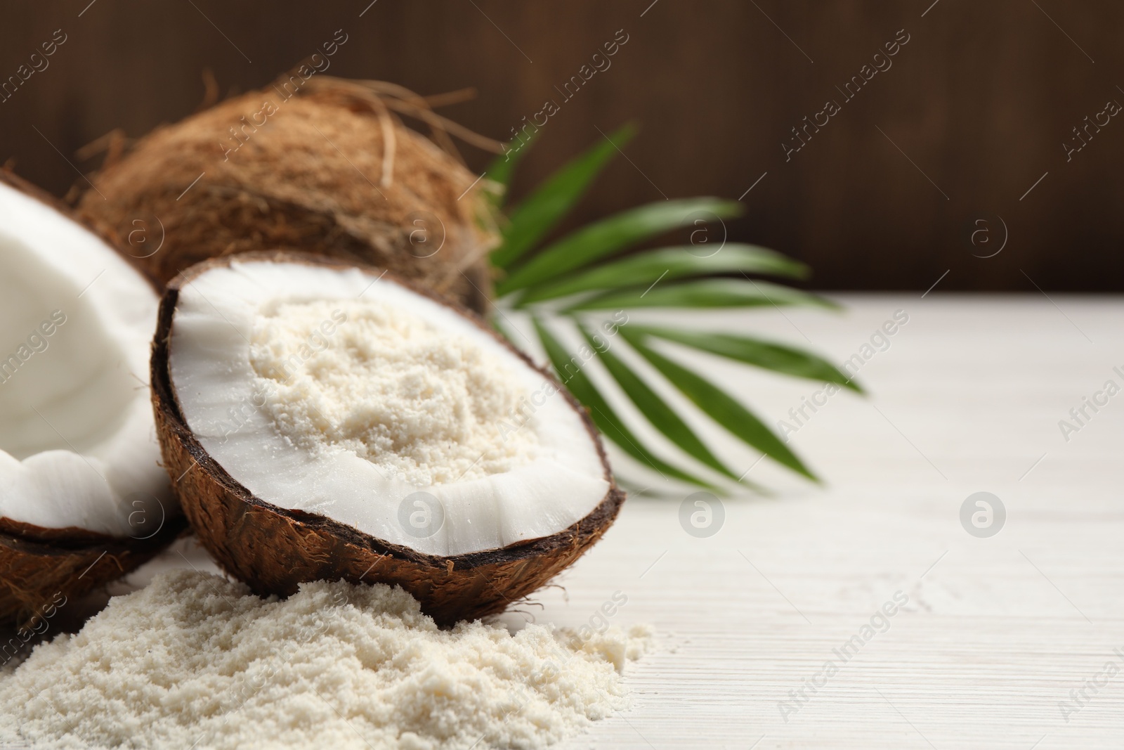 Photo of Fresh coconut flour, nuts and palm leaf on wooden table