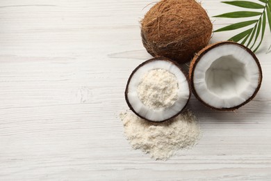 Photo of Fresh coconut flour, nuts and palm leaf on wooden table, space for text