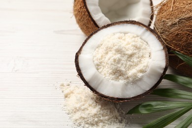 Photo of Fresh coconut flour, nuts and palm leaf on wooden table, space for text