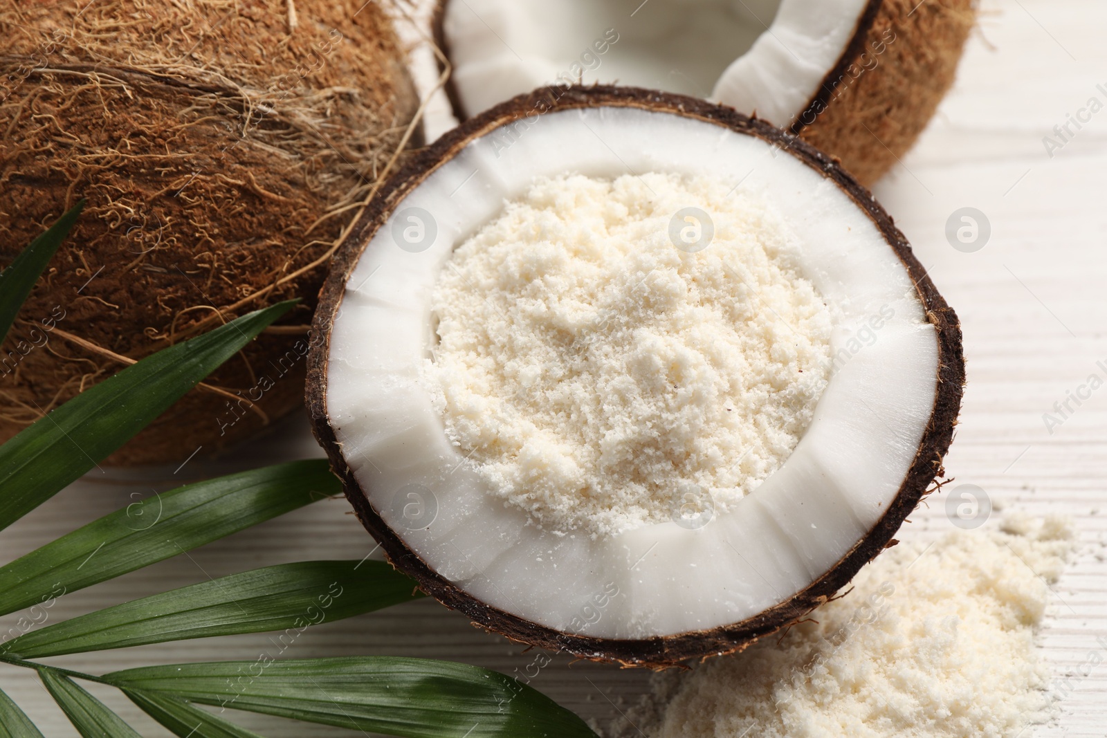 Photo of Fresh coconut flour, nuts and palm leaf on wooden table